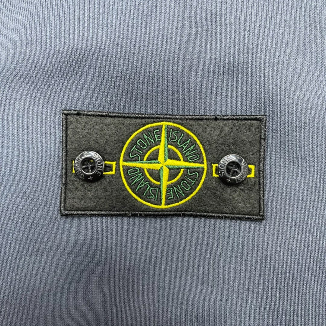 Stone Island logo patch with yellow circular emblem on dark fabric