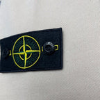 Stone Island logo patch on light beige hoodie with yellow compass emblem