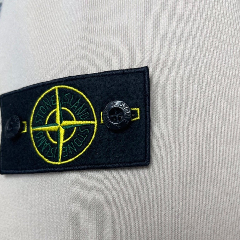 Stone Island logo patch on light beige hoodie with yellow compass emblem