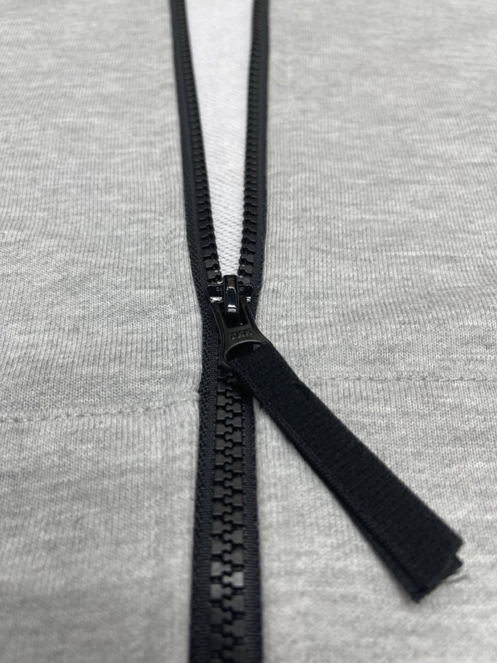Stone Island hoodie zipper pull and black zip tape on light gray marl knit.