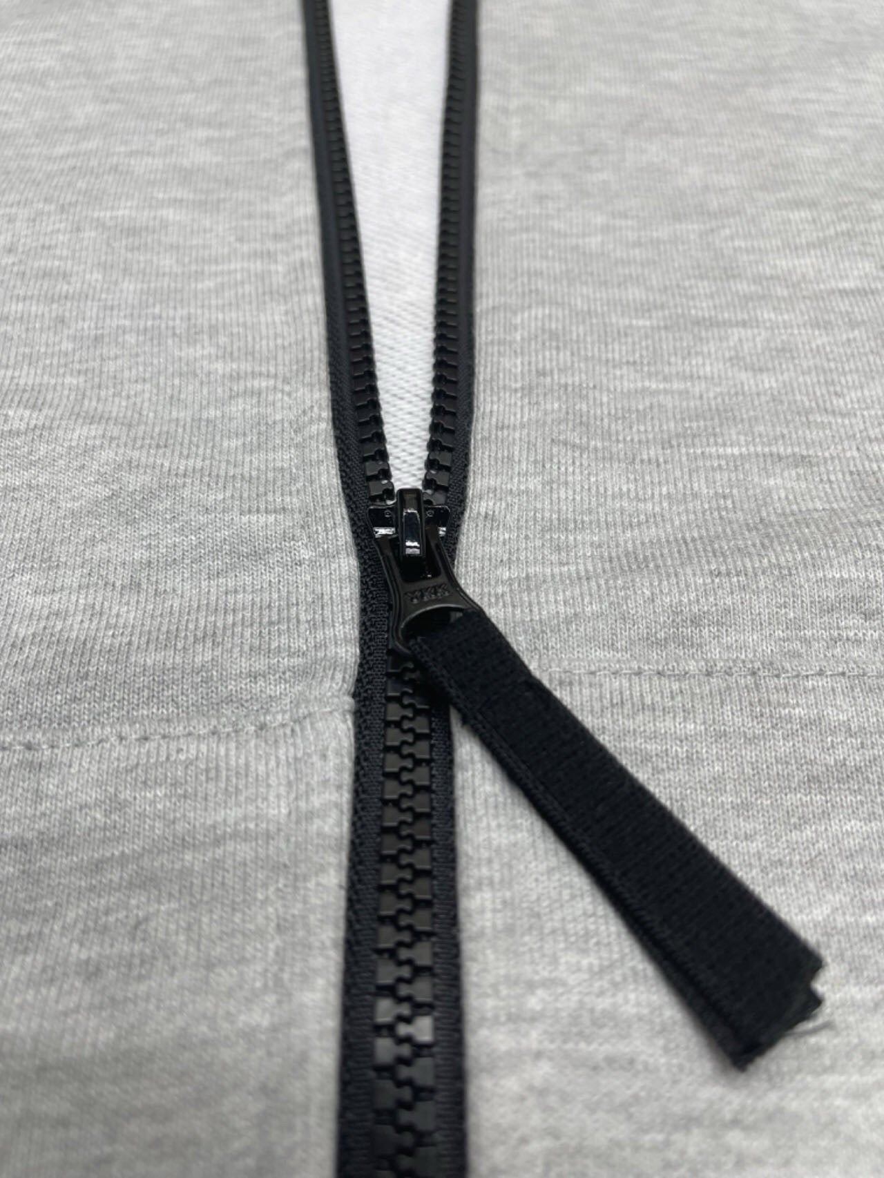 Stone Island hoodie zipper pull and black zip tape on light gray marl knit.