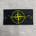 Stone Island chest patch with yellow compass graphic on light gray marl hoodie.