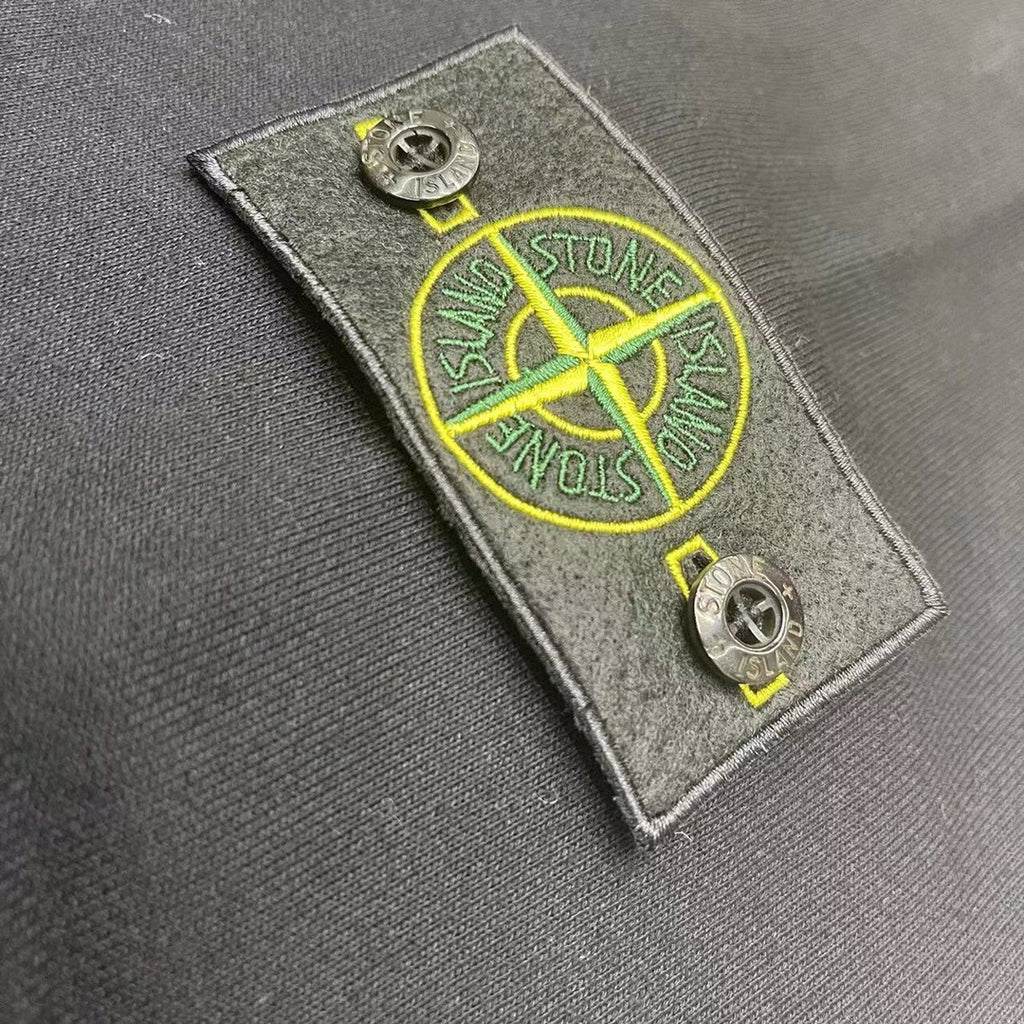 Stone Island patch tag with yellow emblem detail on dark fabric
