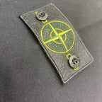 Stone Island patch tag with yellow emblem detail on dark fabric