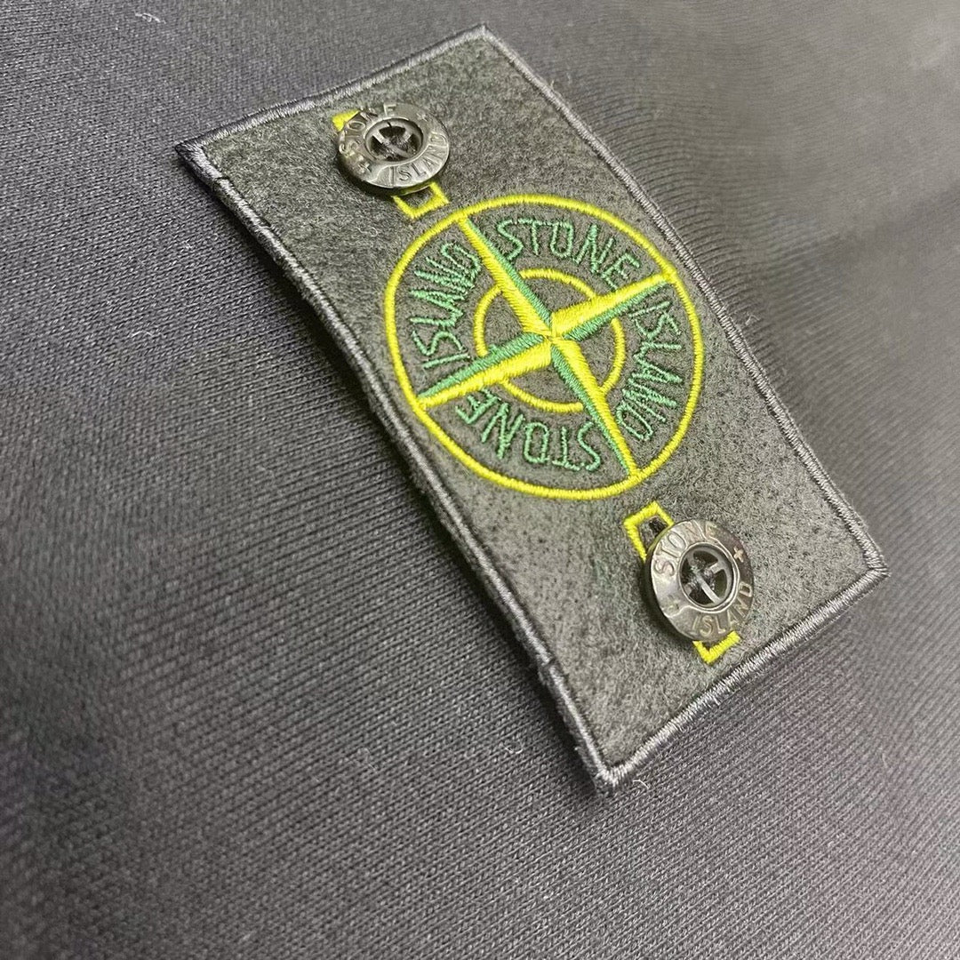 Stone Island patch tag with yellow emblem detail on dark fabric