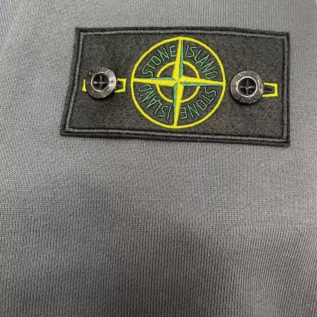 Stone Island logo badge with crossed lines on gray fabric