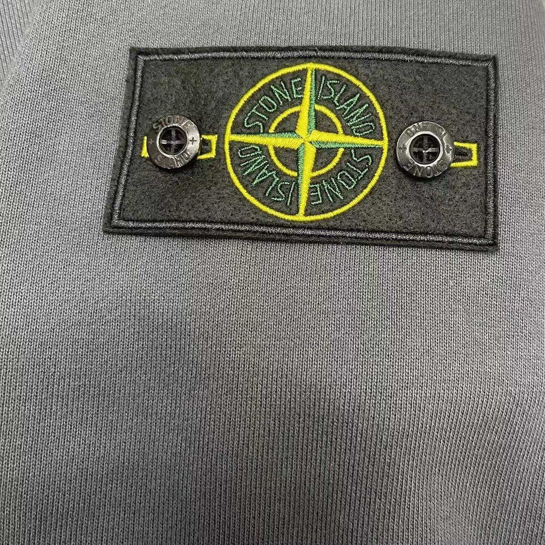 Stone Island logo badge with crossed lines on gray fabric