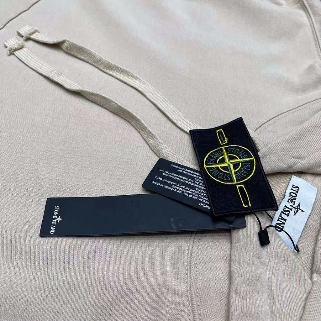 Cream hoodie chest close-up with drawstring, pocket seam, and hang tags