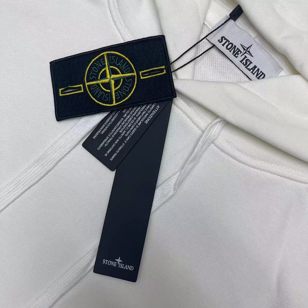White Stone Island hoodie fabric with navy label and yellow emblem near hood