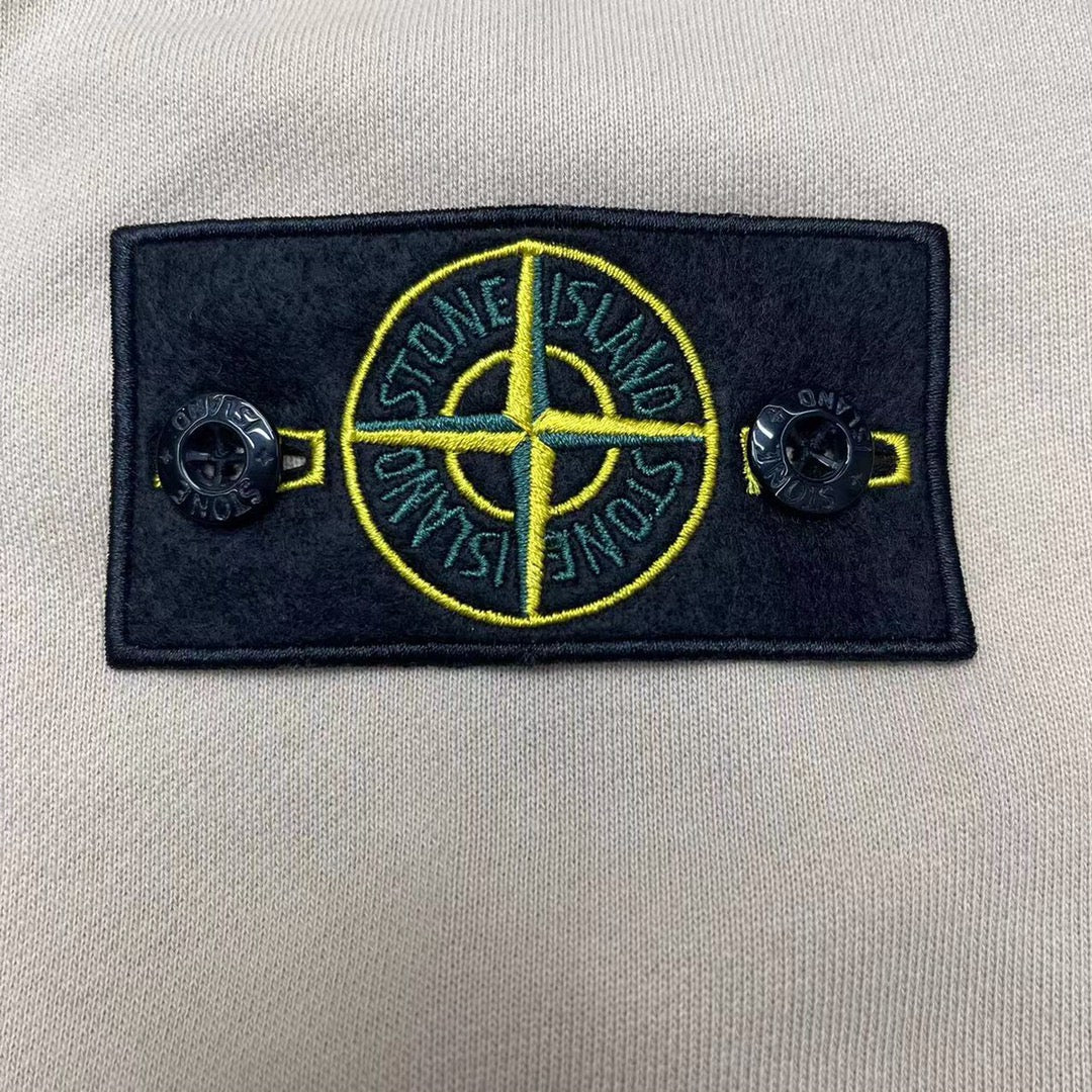 Stone Island logo patch on cream hoodie chest, dark fabric with yellow graphic