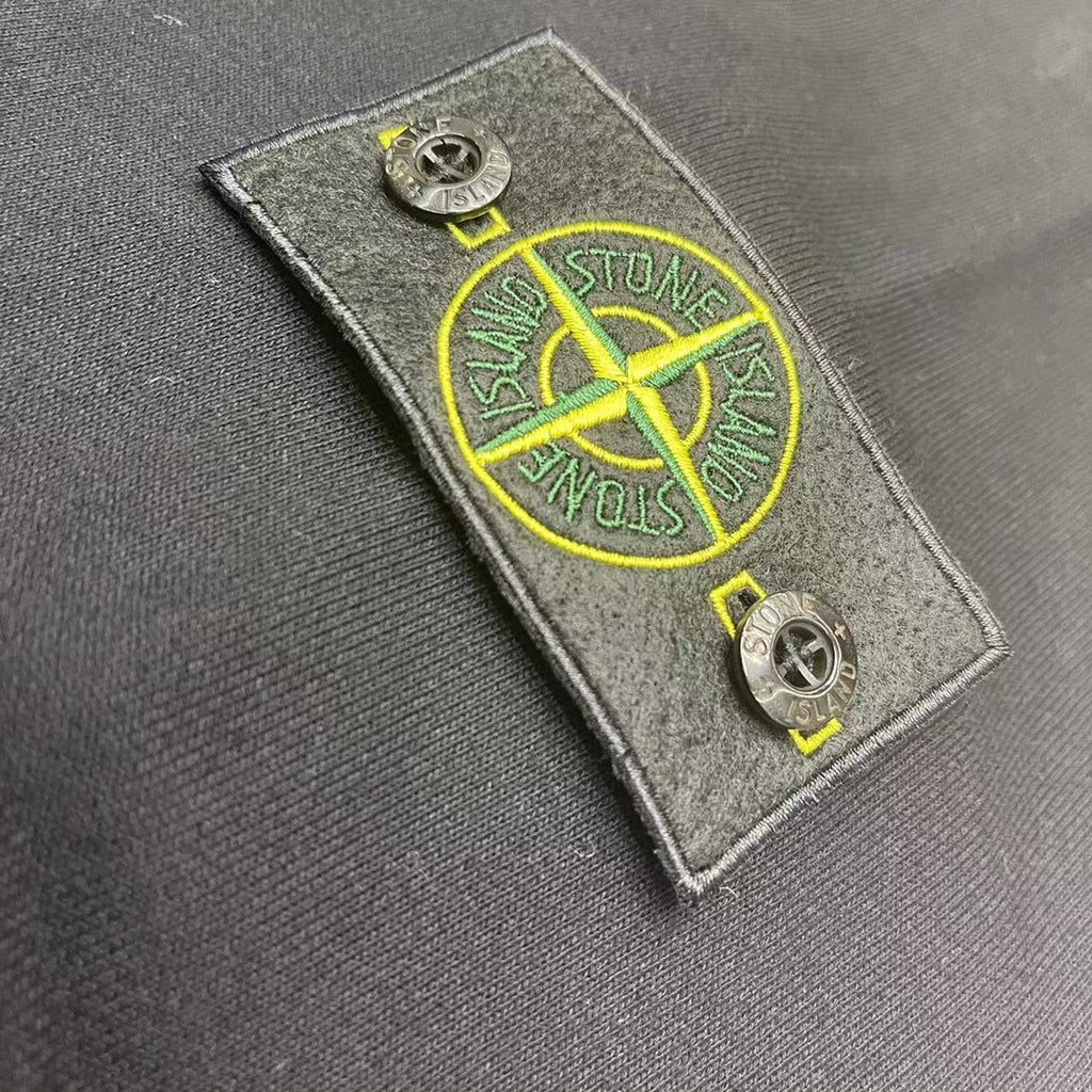 Gray hooded sweatshirt close-up of yellow logo patch on fabric