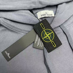 Stone Island neck label close-up with hang tags on slate blue hood