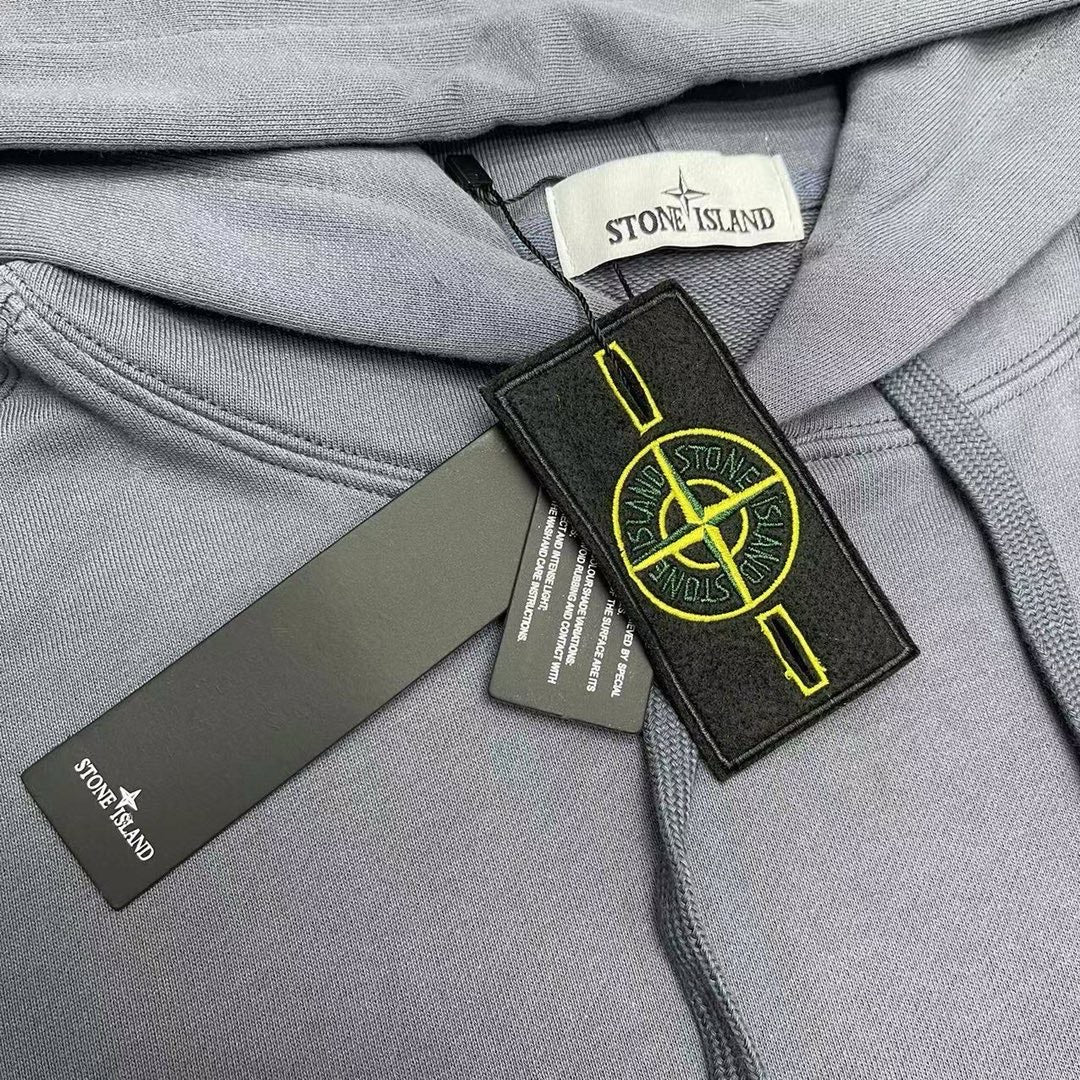 Stone Island neck label close-up with hang tags on slate blue hood