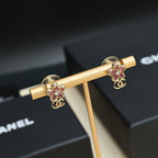 Chanel floral earrings with pink stones and gold-tone CC emblem on gold stand