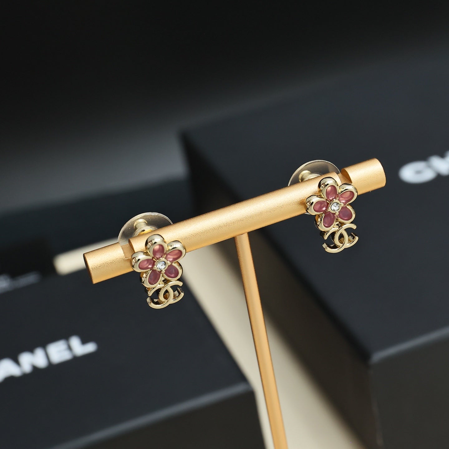 Chanel floral earrings with pink stones and gold-tone CC emblem on gold stand