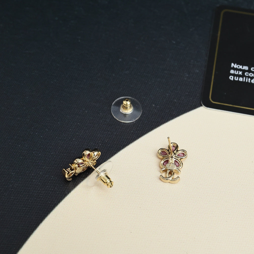 Chanel floral earrings with gold-tone CC detail and pink stones on dark fabric