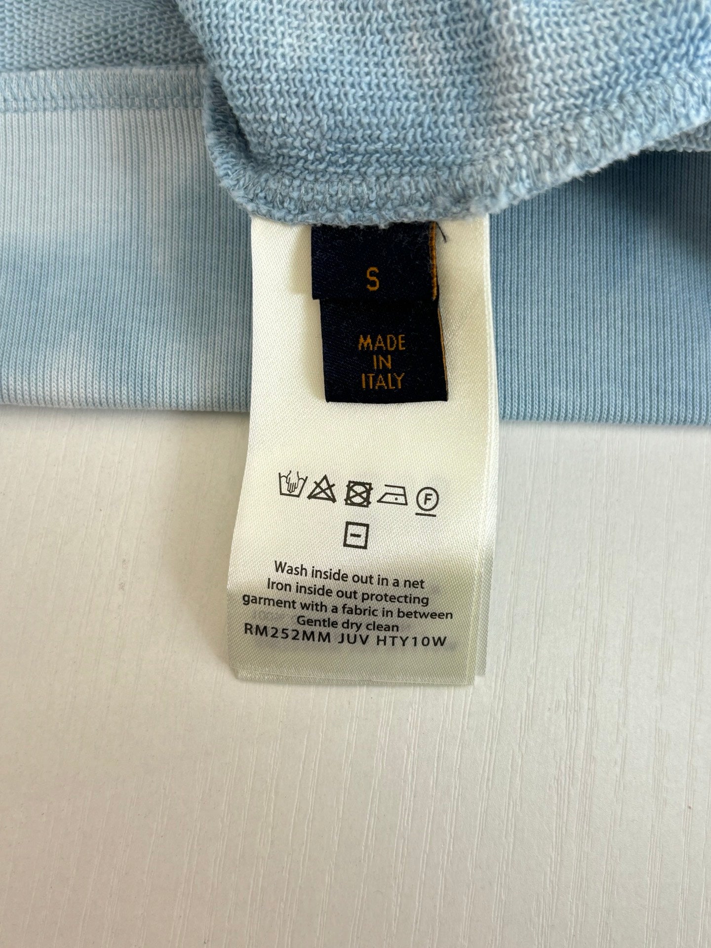 Light blue long-sleeve knit top with care label and Made in Italy tag