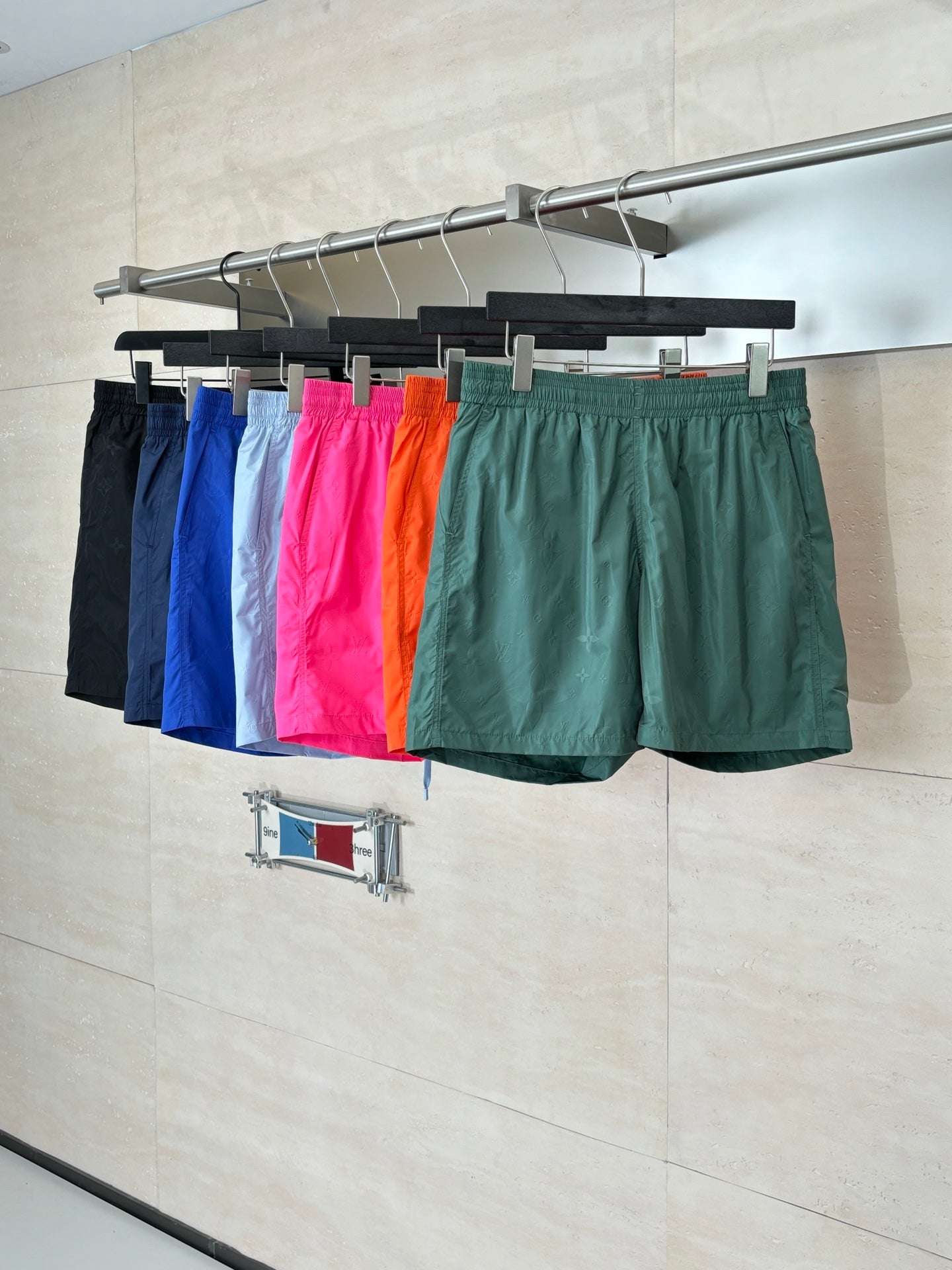 Colorful Louis Vuitton shorts on rack: blue, pink, orange, green, and black.