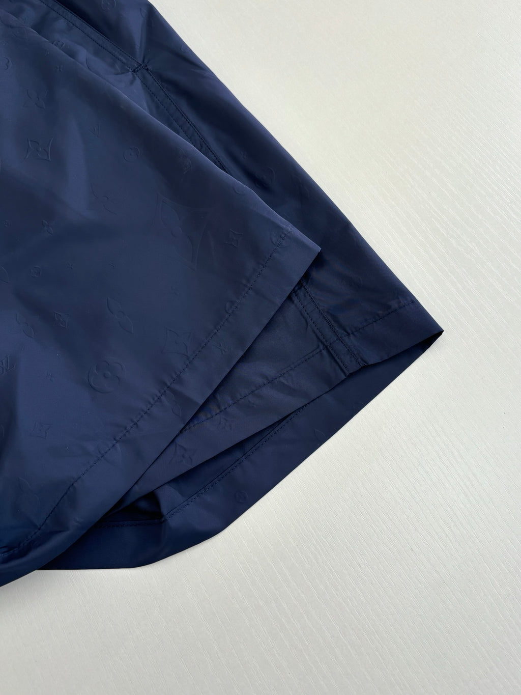 Navy shorts hem detail with diagonal seam and tonal logo pattern