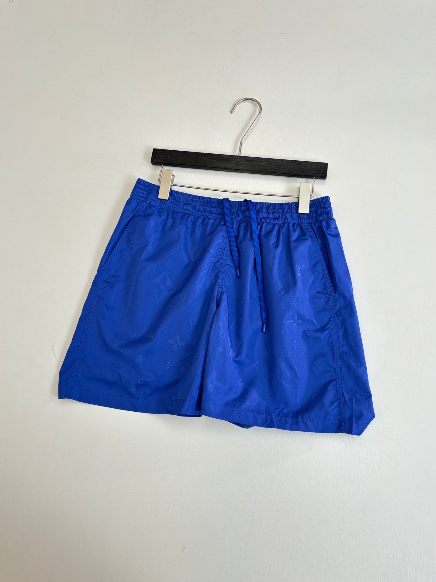 Blue shorts with drawstring and elastic waistband on a hanger