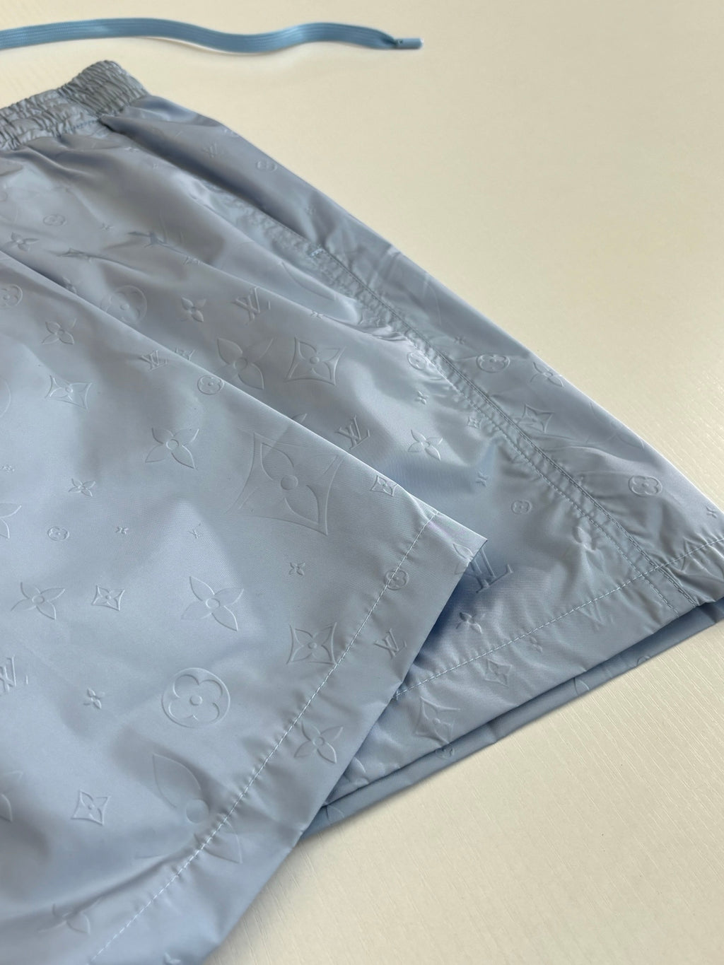 Light blue monogram shorts fabric close-up with side seam