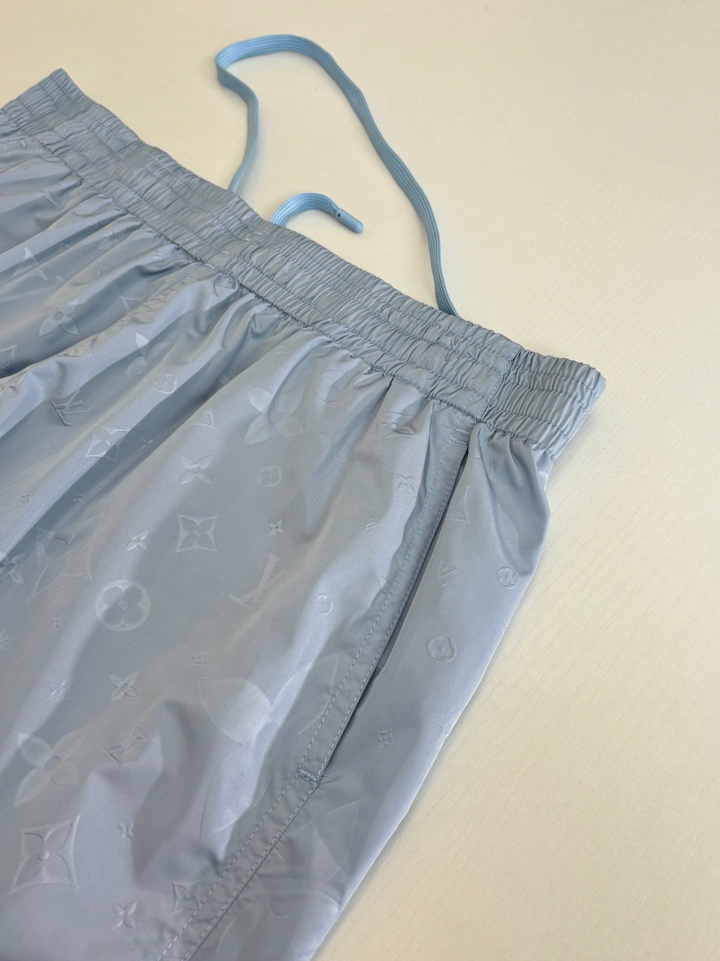 Close-up of light blue monogram shorts with drawstring and elastic waist