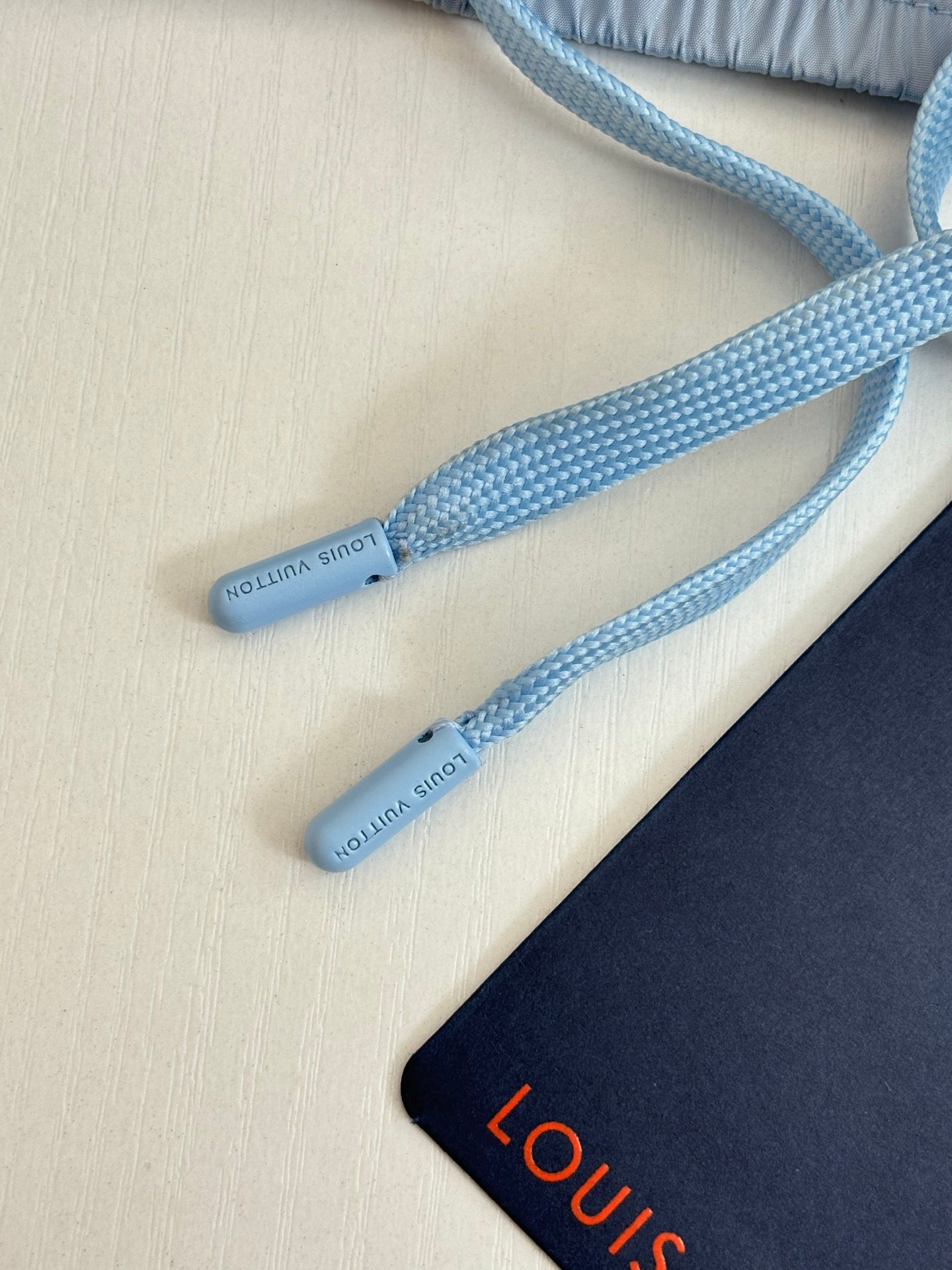 Light blue drawstrings with small printed text on monogram shorts