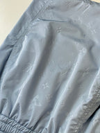Light blue monogram fabric close-up on shorts, showing embossed pattern