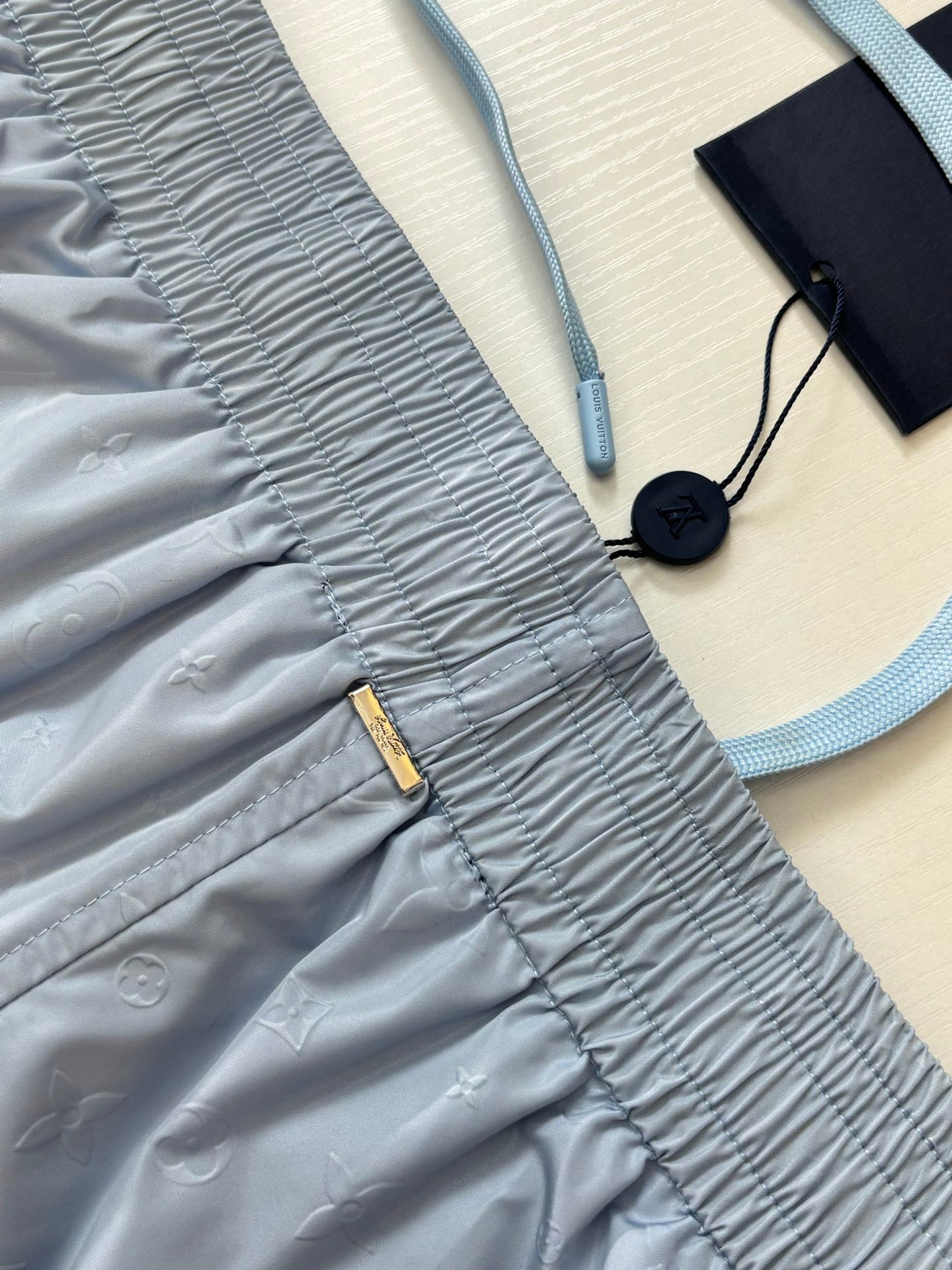 Light blue monogram shorts detail with ruched waistband and zip pocket