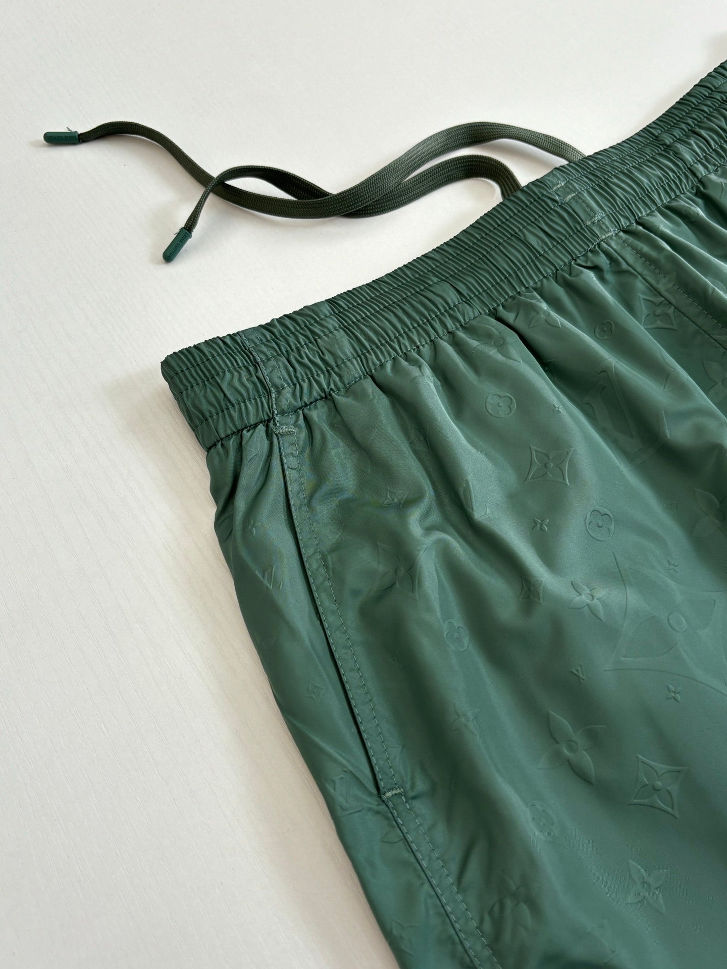 Green Louis Vuitton shorts close-up showing drawstring and gathered elastic waist.
