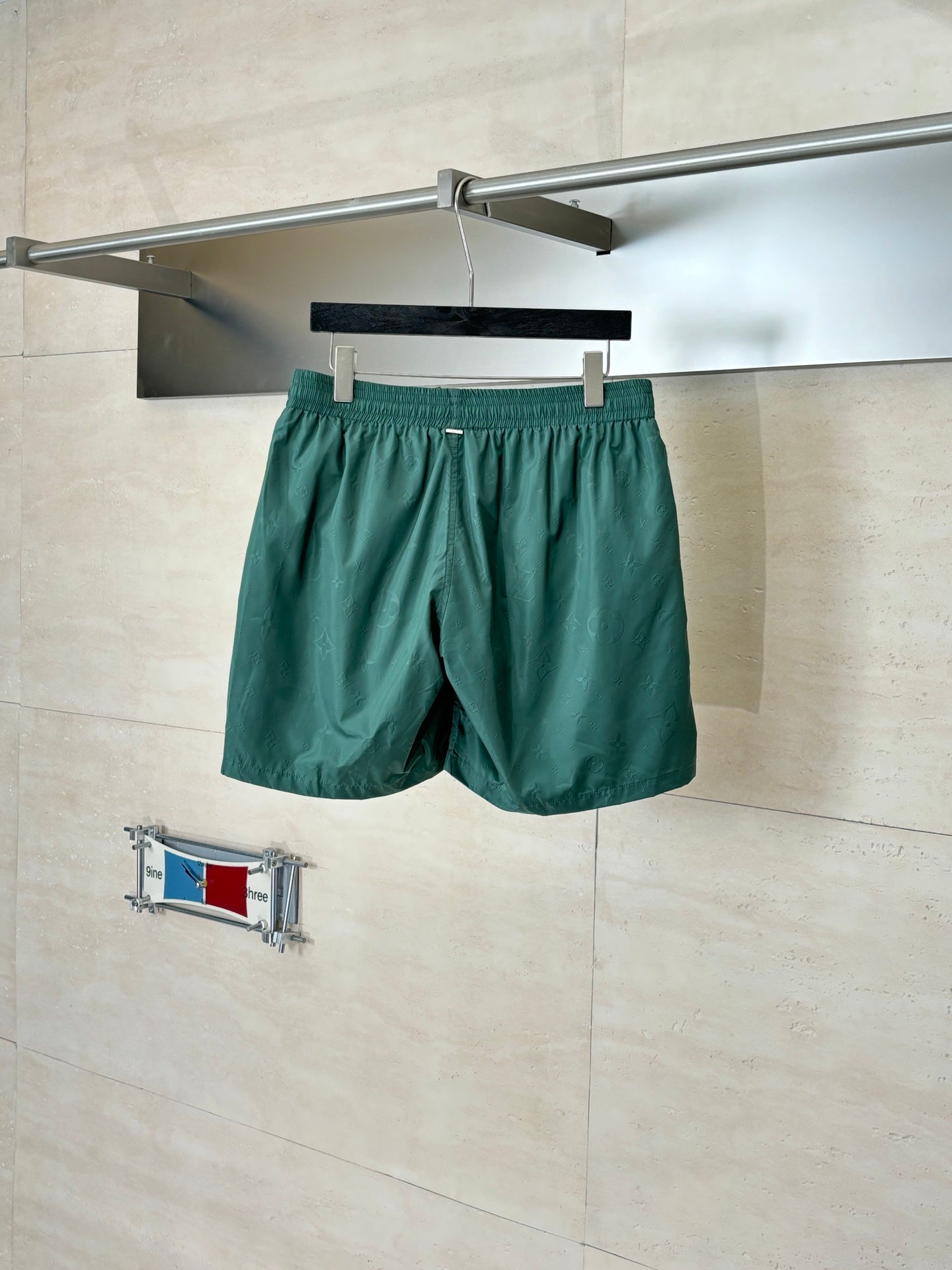 Green Louis Vuitton shorts on hanger, elastic waistband and adjustable drawstring.