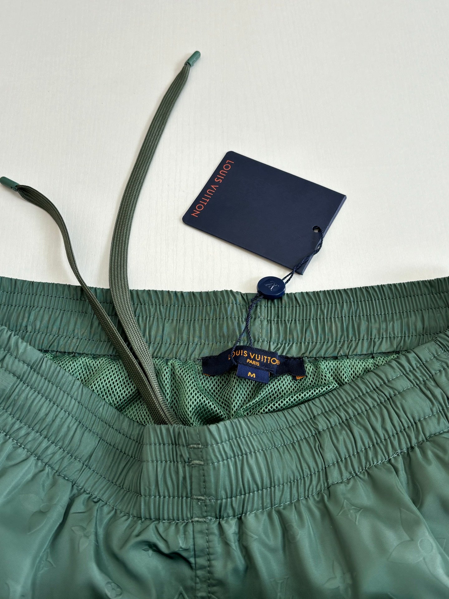 Green Louis Vuitton shorts waistband with inside label and navy hang tag.