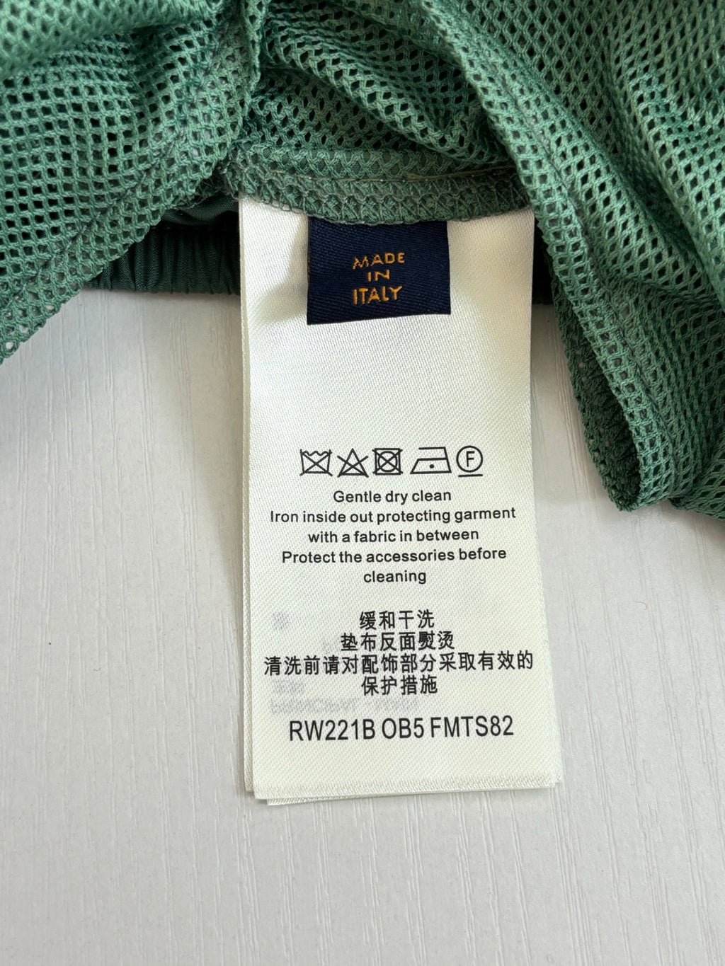 Louis Vuitton pants care label on green textured fabric