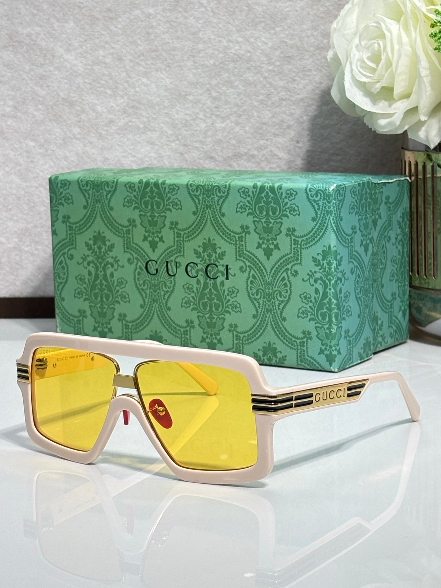 White Gucci glasses with gold trim and yellow mirrored lenses