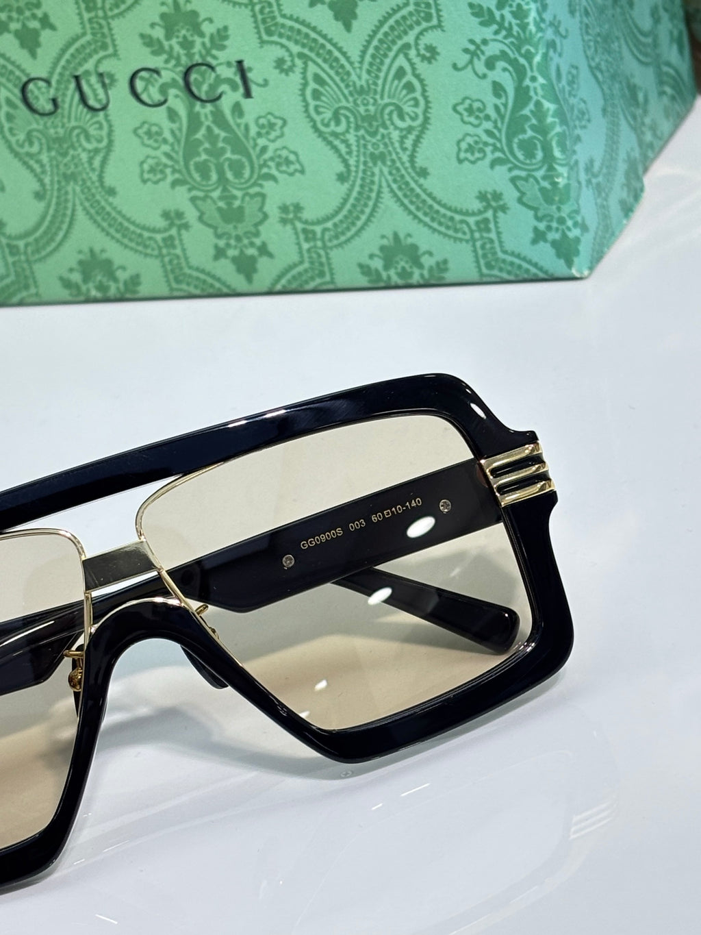Gucci sunglasses detail, black frame with gold trim and beige-tinted lenses