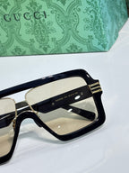 Black Gucci glasses with gold hinge hardware and tinted lenses