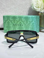Gucci sunglasses with black oversized square frames, gold stripes, and dark lenses