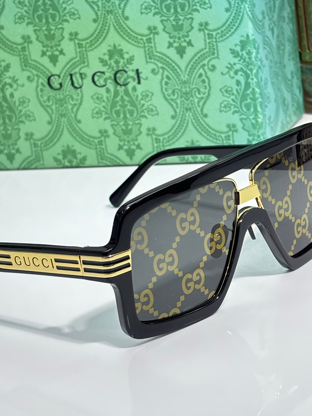 Gucci sunglasses three-quarter view with black frames and gold stripe temple detail
