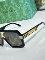 Gucci sunglasses side view with black frames and gold stripe logo detailing