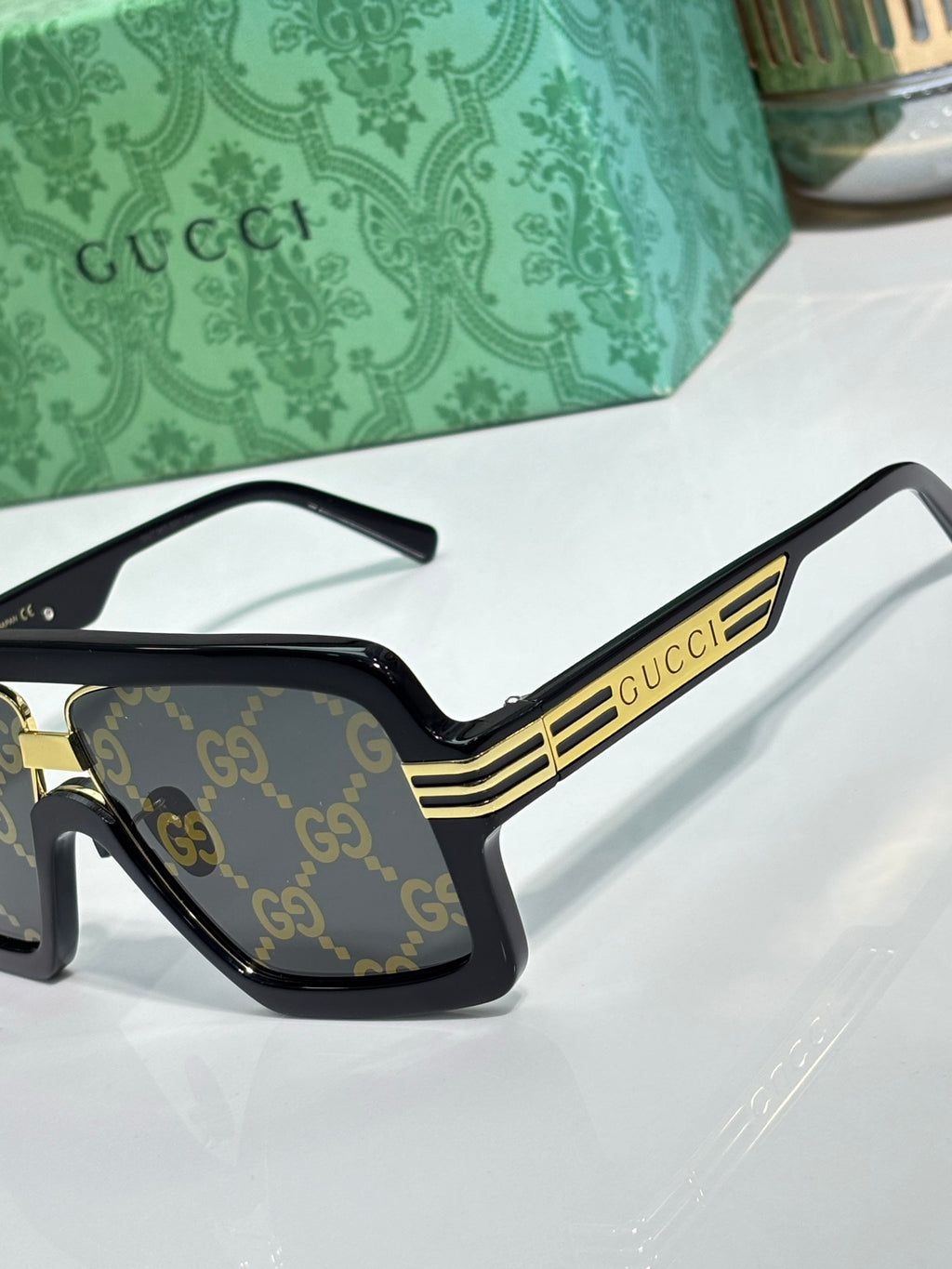 Gucci glasses close-up of front-left frame with gold bar and GG logo lenses