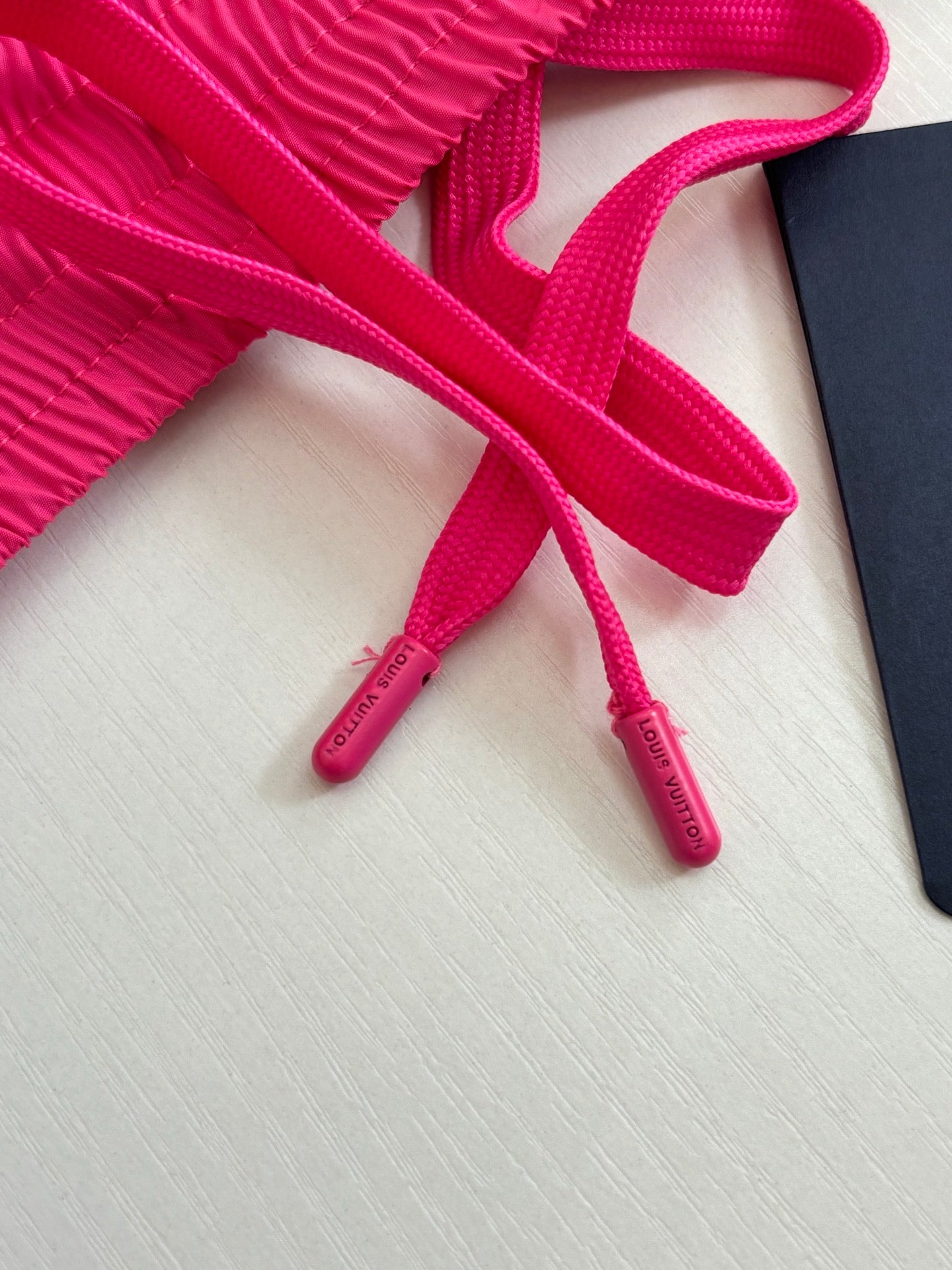 Bright pink drawstring cords with plastic tips attached to shorts