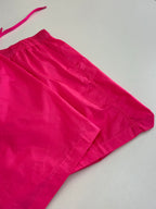 Pink shorts with structured hem and stitched panels at the side