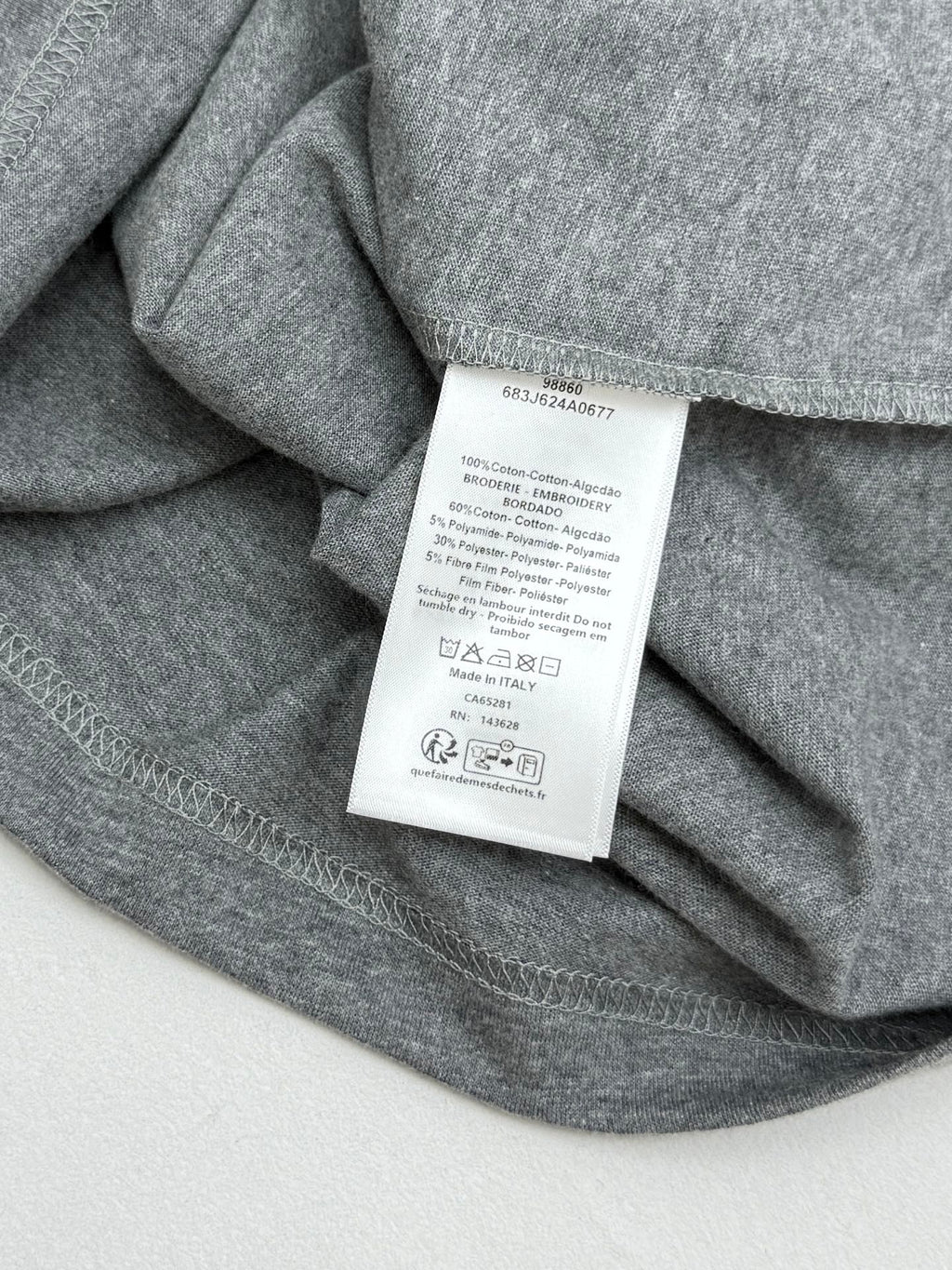 Grey T-shirt fabric with white care tag sewn at inner neck