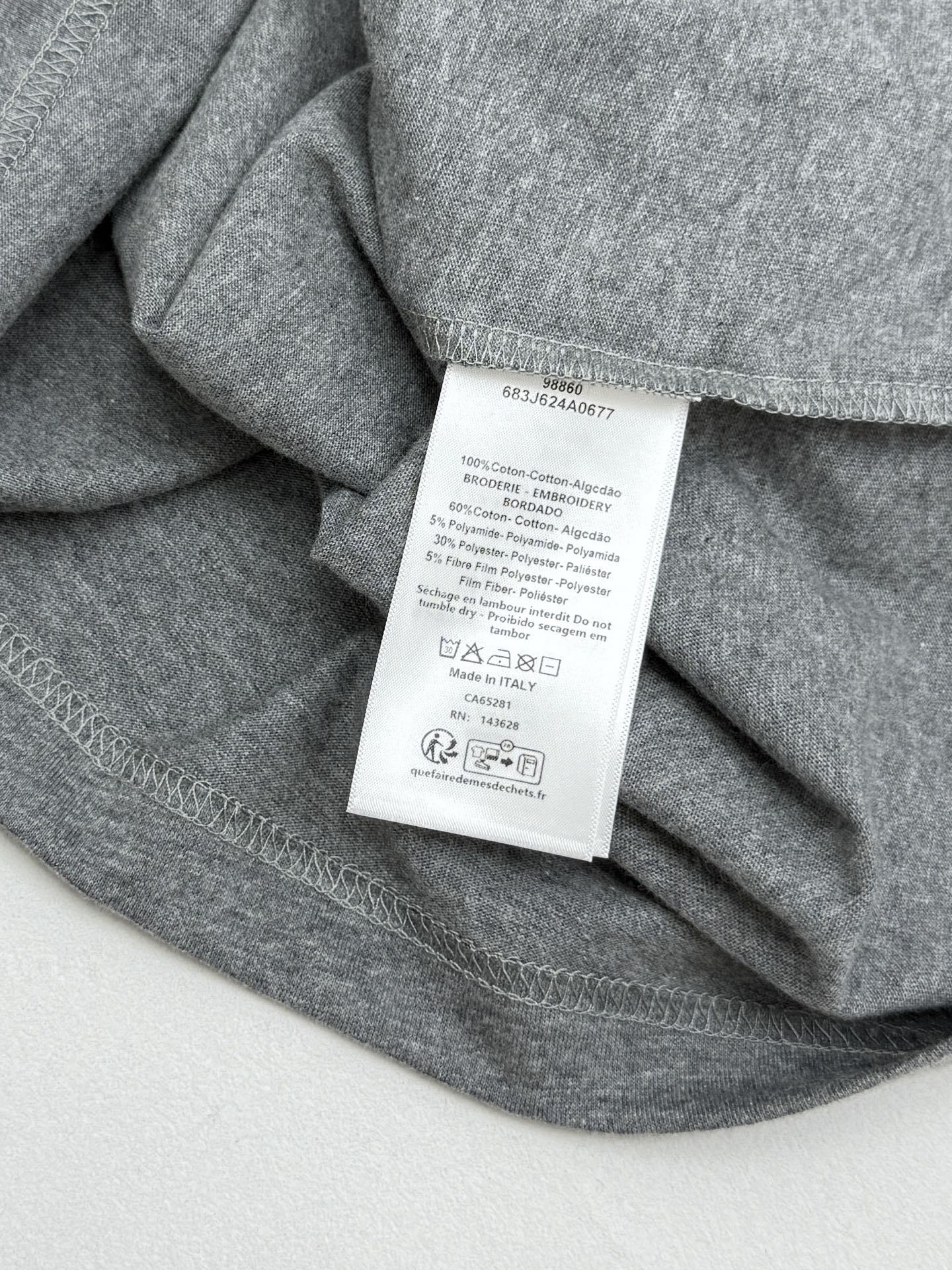 Grey T-shirt fabric with white care tag sewn at inner neck