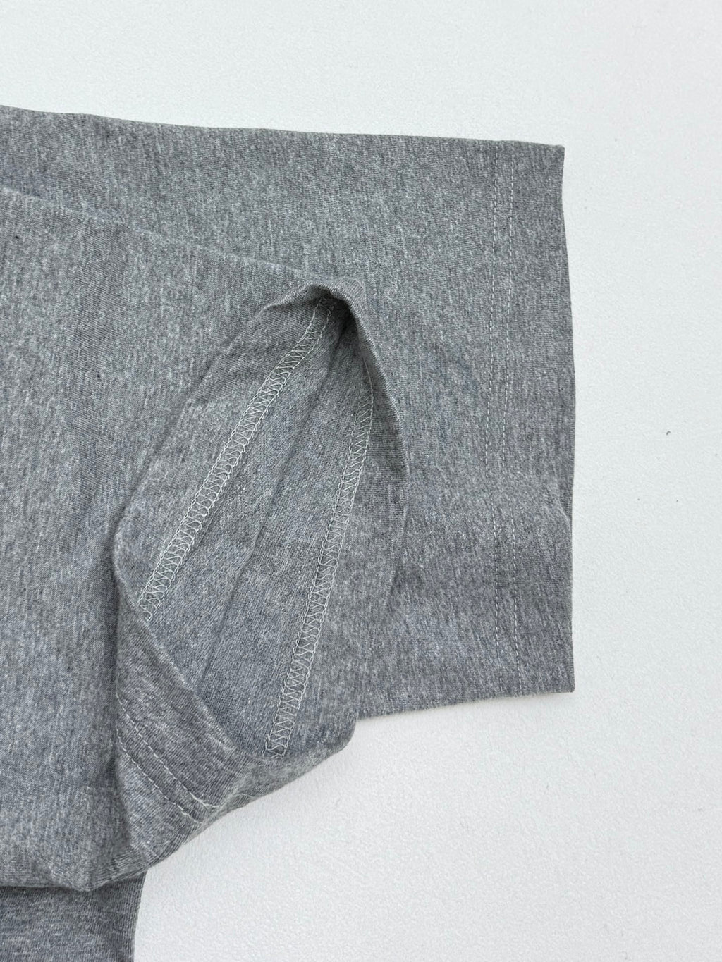 Grey T-shirt sleeve with stitched seam and folded hem