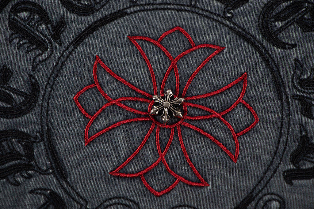 Embroidered circular skull-flower graphic with red petals on dark fabric