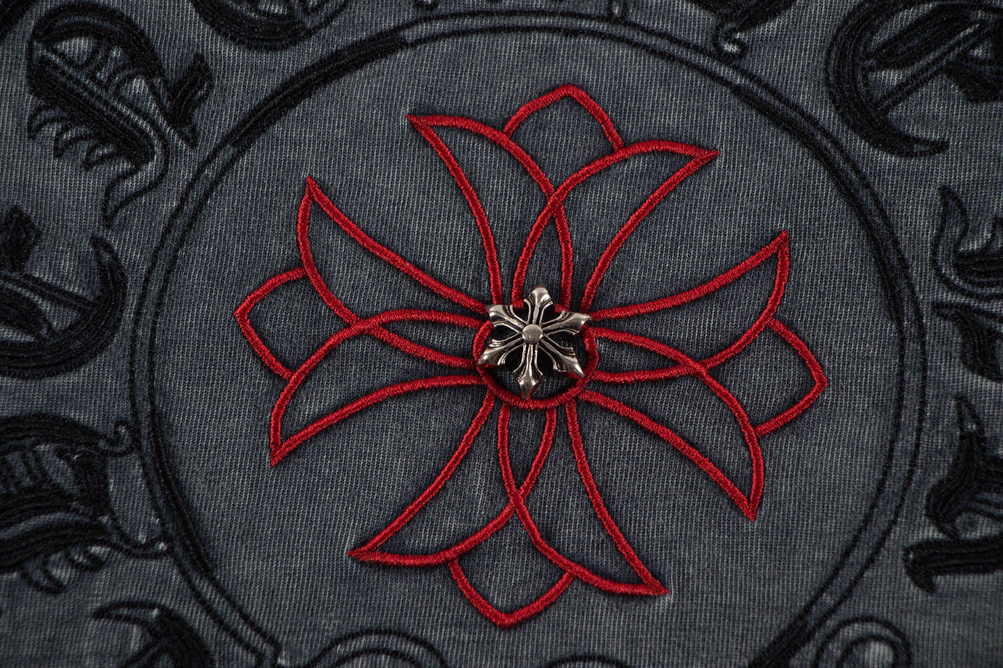 Embroidered circular skull-flower graphic with red petals on dark fabric