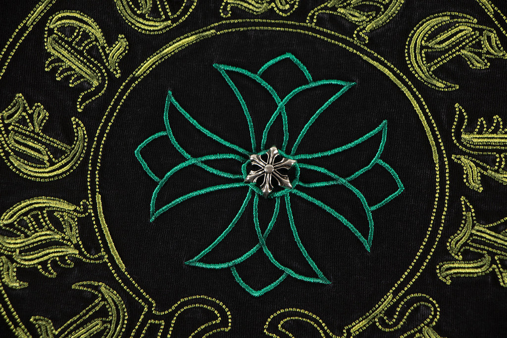 Embroidered-style teal flower center with gold ornamental patterns on T-shirt