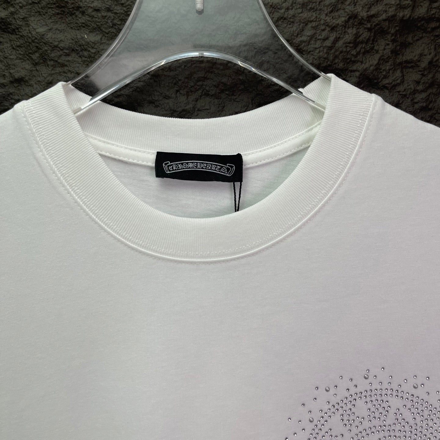White crewneck T-shirt with ribbed collar and rhinestone logo at hem