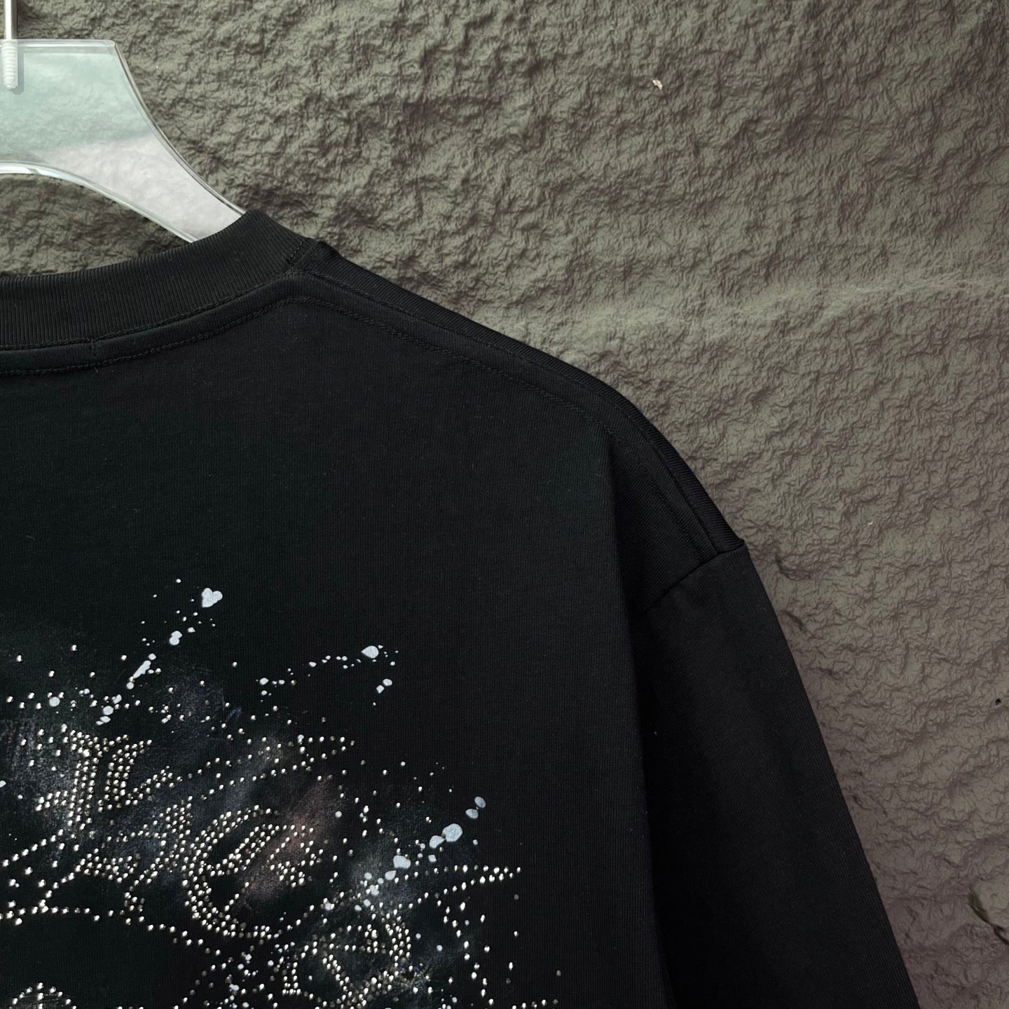 Black short-sleeve T-shirt with partial rhinestone graphic on upper back.